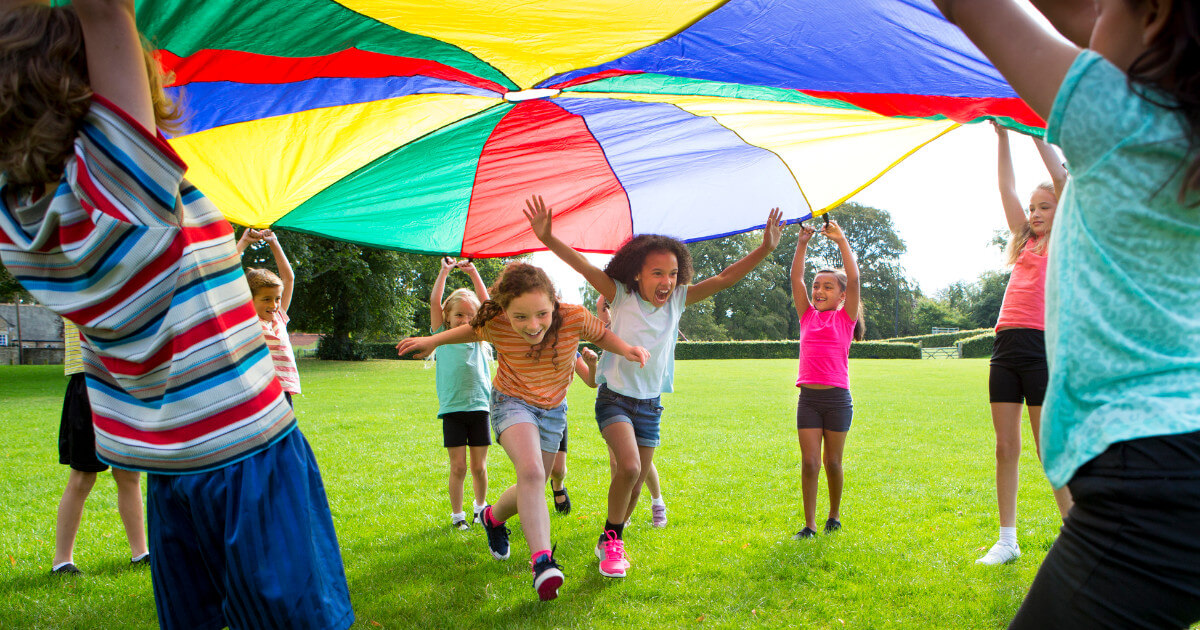 Kids Activity, kids running under a giant parachute in the park.