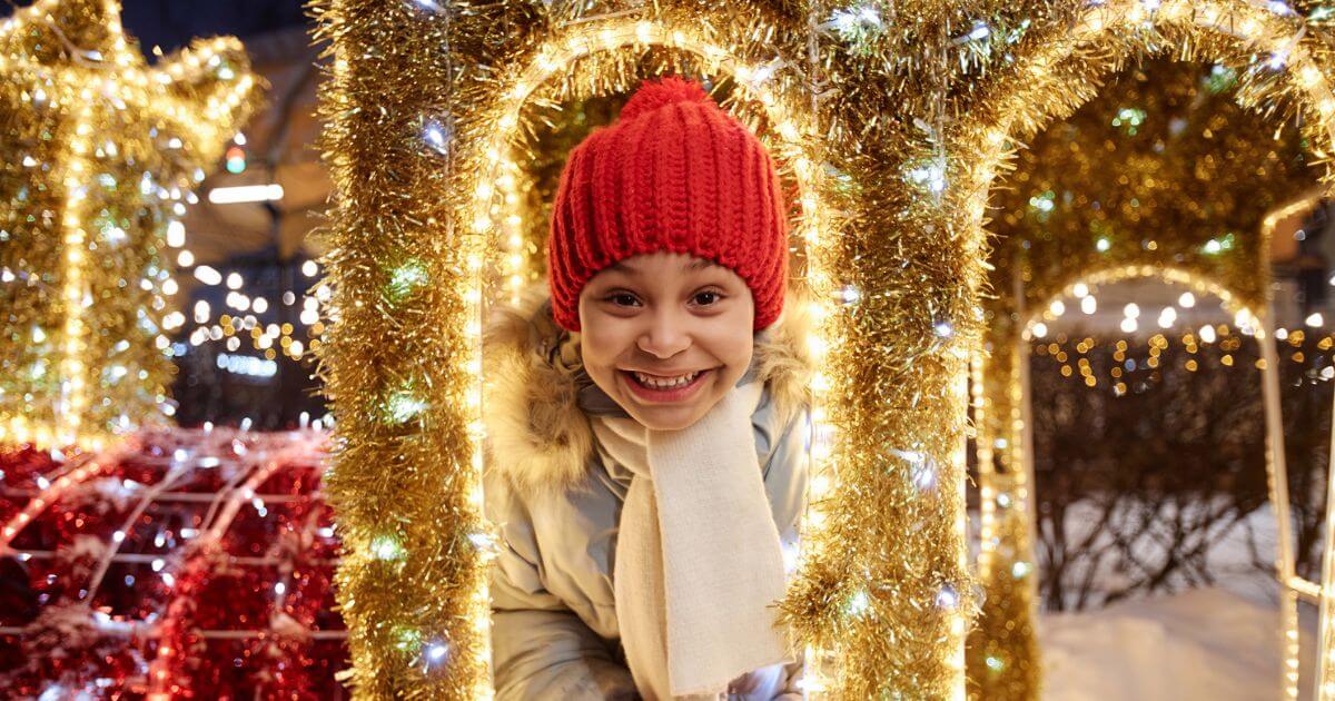 Kid Smiling in the Park with Holiday Lights