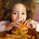 Happy kid child eating hamburger smiling