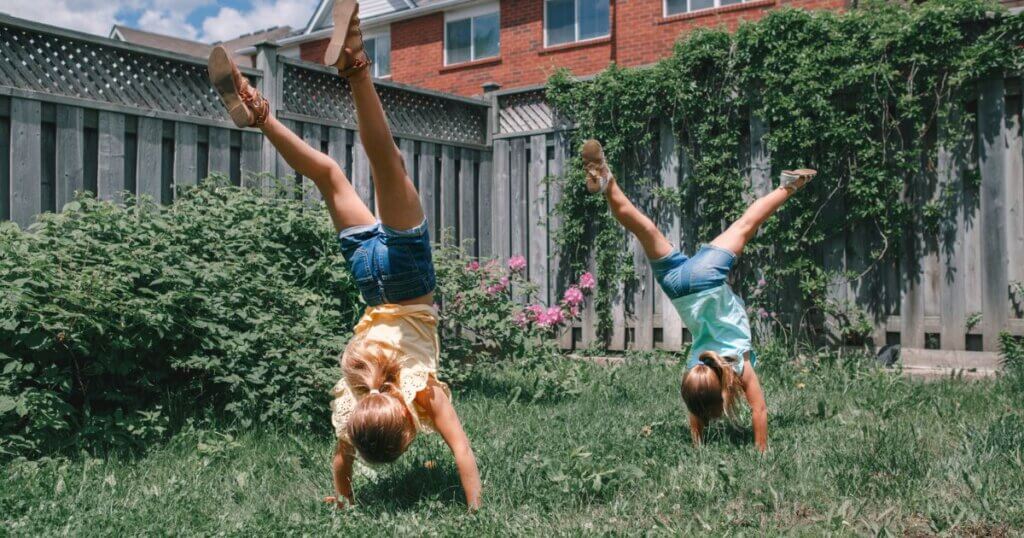 Sisters doing gymnastics together in their backyard cartwheels and handstands