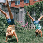 Girls do gymnastics in backyard.