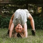 child gymnast doing back bend in grass during gymnastics floor routine